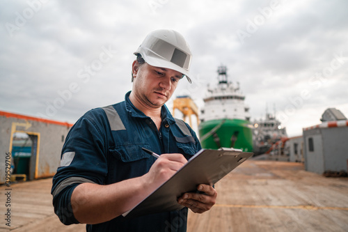 Φωτογραφία Marine Deck Officer or Chief mate on deck of offshore vessel or ship doing check and filling checklist