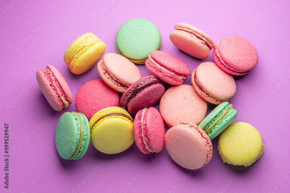 Fototapeta premium Colorful sweet macarons or macaroons, flavored cookies on purple background.