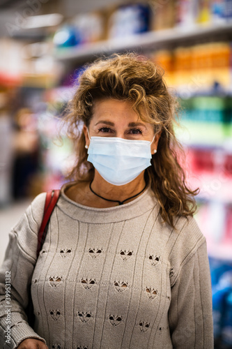 Mature woman smiling to camera while wearing mask in supermarket