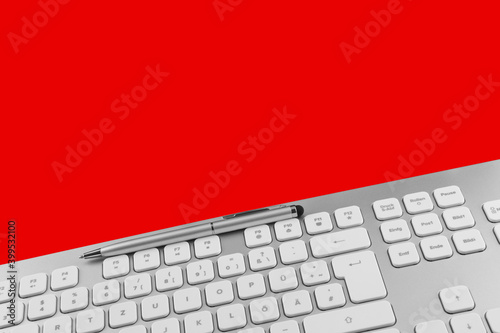 PC keyboard and pen against red background photo