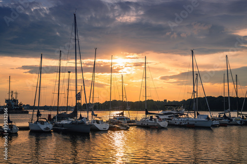 Colorful sunset above the sea with sail boats in Germany, Rostock. Reflected sun on a water surface. Seascape, Summer and travel vacation concept © eplisterra