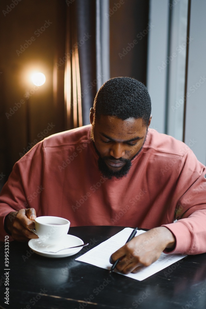 Young handsome dark-skinned businessman drinks coffee in a cafe. Young handsome dark-skinned businessman drinks coffee in a cafe.