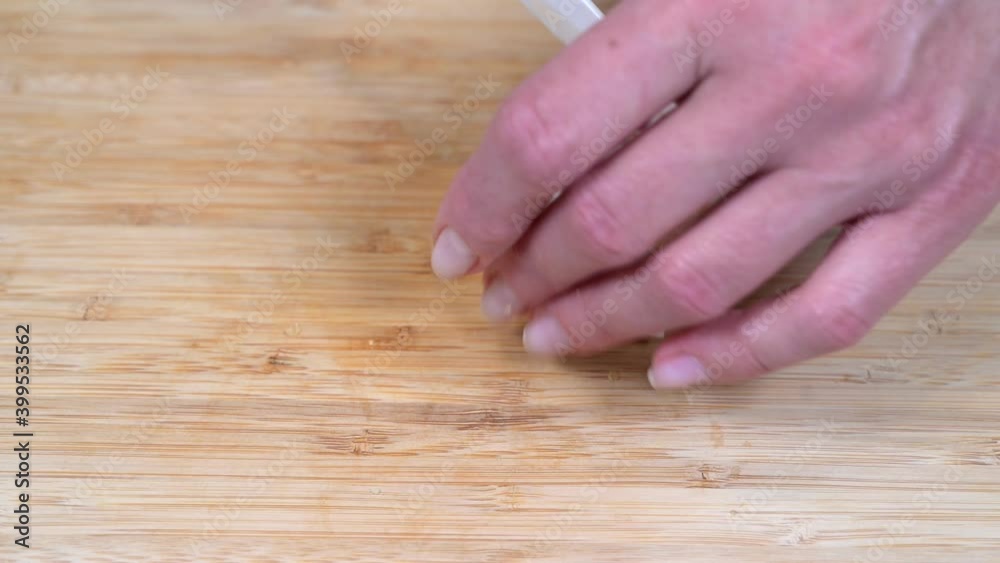 Female hand cuts egg with a white ceramic knife on a wooden cutting board, close up 4k Female hand cuts egg with a white ceramic knife on a wooden cutting board, close up 4k