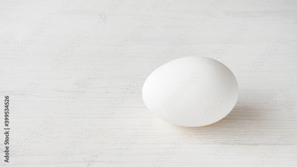 Single whole egg in a white shell on a wooden background Single whole egg in a white shell on a wooden background