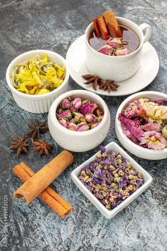 sidewise view of herbal tea and cinnamon sticks and dry flowers on grey background