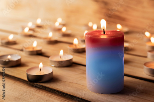 Candles on a wooden background. A red sick candle that changes color when you light it and small candles. Shallow depth of field.