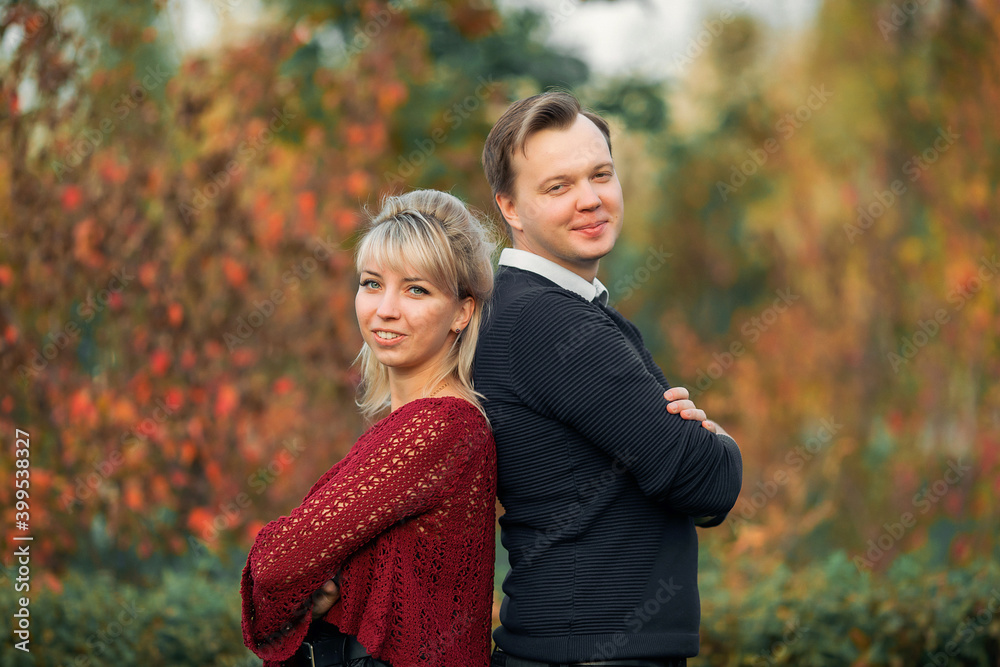 blonde girl in maroon sweater, brown-haired young man in blue sweater hug in the Park blonde girl in maroon sweater, brown-haired young man in blue sweater hug in the Park