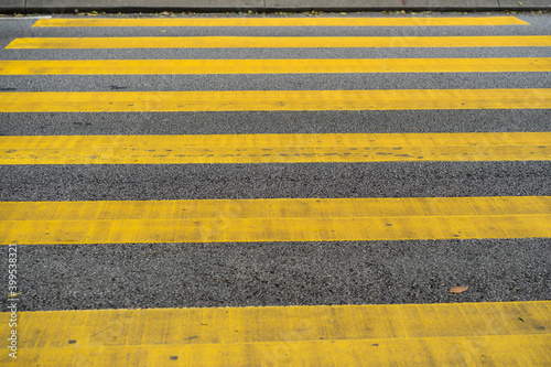 Cars and motorcycles are passing through the pedestrian crossing. Yellow stripes of the crosswalk. photo