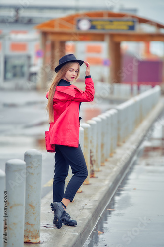 young business woman near factory building in red coat and hat