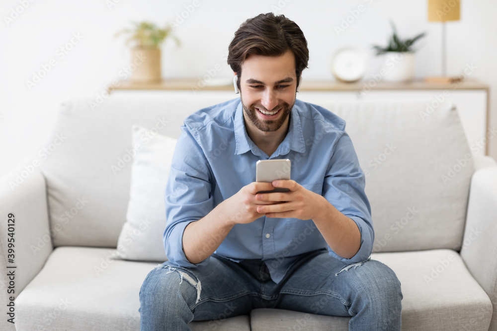 Happy Man In Earbuds Making Video Call On Smartphone Indoors