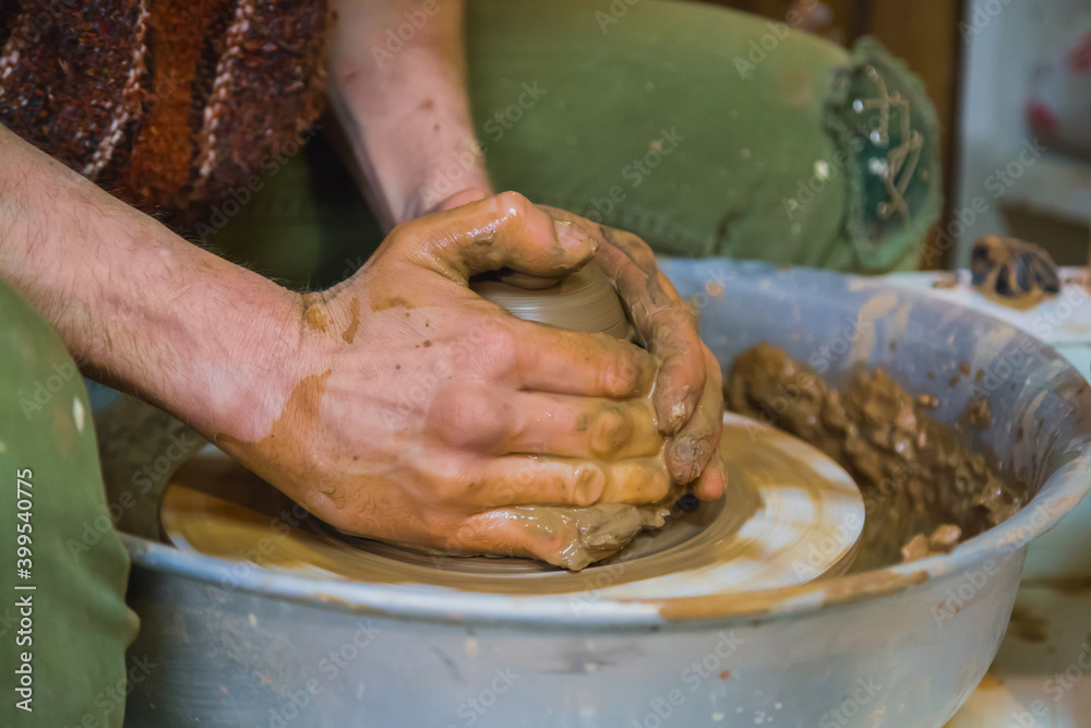 Close up view - professional male potter making pot on pottery wheel at workshop, studio. Handmade, art and handicraft concept