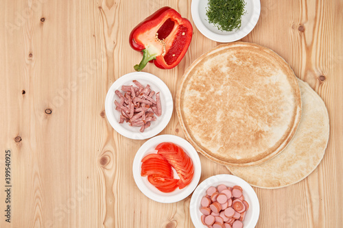 Composition of fresh pizza ingredients on a light wooden background. Cooking pizza. Top view with copy space.