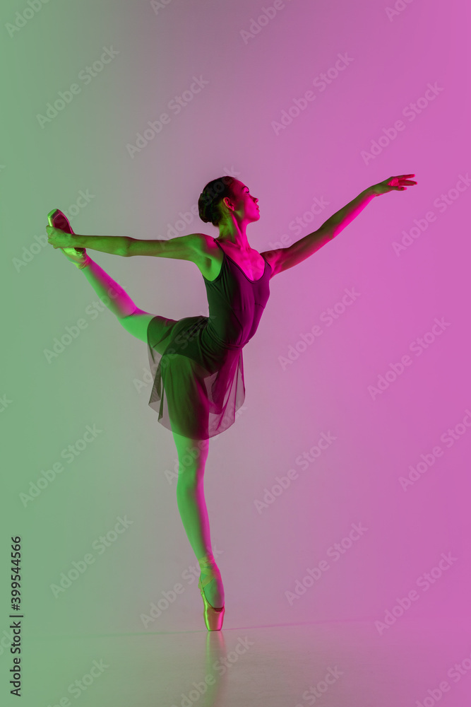 Target. Young and graceful ballet dancer isolated on gradient pink-green studio background in neon. Art, motion, action, flexibility, inspiration concept. Flexible ballerina, weightless jumps. Target. Young and graceful ballet dancer isolated on gradient pink-green studio background in neon. Art, motion, action, flexibility, inspiration concept. Flexible ballerina, weightless jumps.