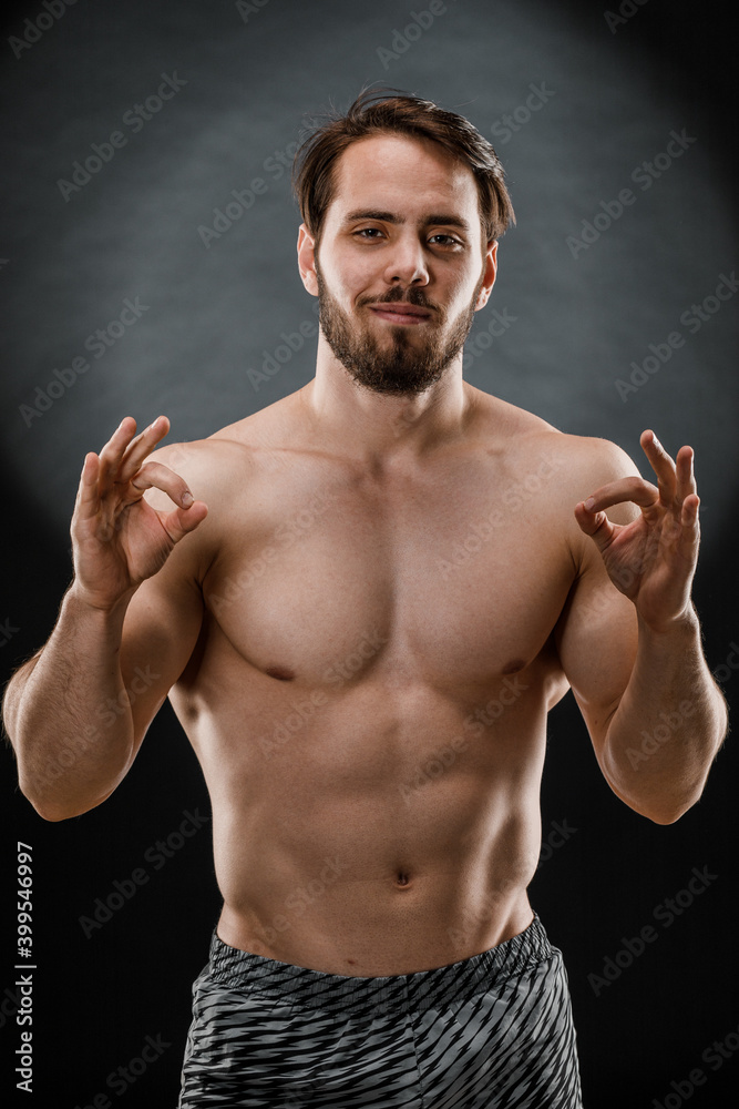 A handsome muscular man without a t-shirt poses for a photographer in a dark photo Studio. The concept of sport