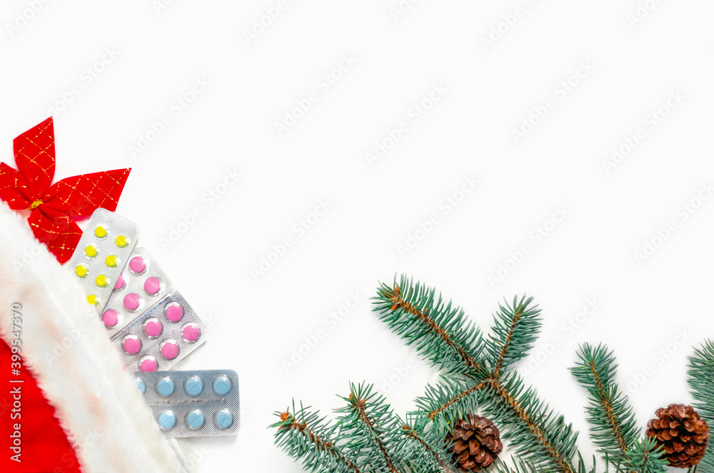 Christmas banner with medical supplies. Packs of pills under a Christmas red cap, near a green branch of a Christmas tree on a white background. Christmas card for doctors concept. Copy space.