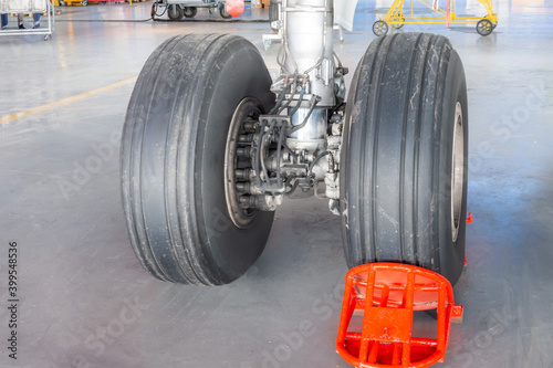 Landing gear airplane in hangar chassis rubber close-up, wheel supported by a brake red shoe.