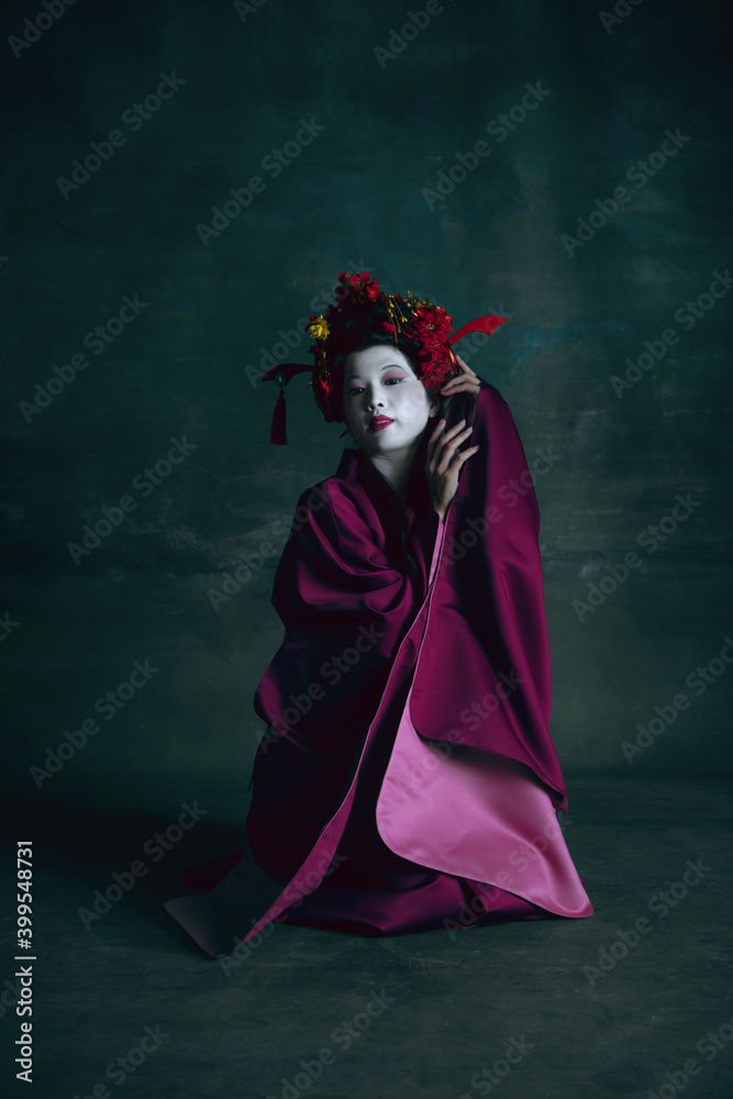 Beauty. Young japanese woman as geisha isolated on dark green background. Retro style, comparison of eras concept. Beautiful female model like bright historical character, old-fashioned.