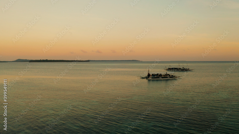 Morning on a tropical island during sunrise and boats on the sea surface. Sunrise over ocean. Balabac, Palawan, Philippines