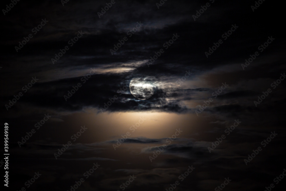 Full moon behind clouds on black sky, dramatic sky, horror sky