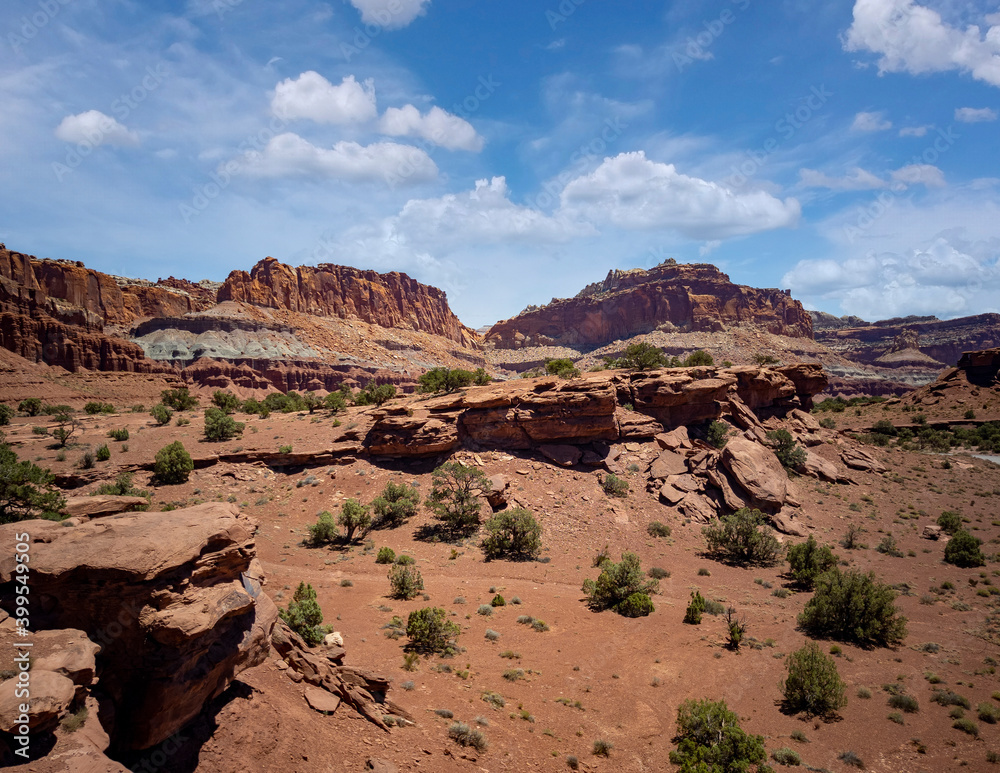 Fototapeta premium Amazing sandstone monoliths in a barren desert prairie on a blue partly cloudy summer day at Capitol Reef National Park in Torrey Utah