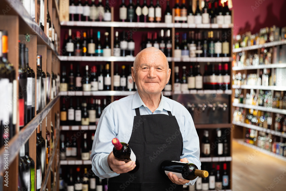 Glad positive senior male vintner giving recommendation about purchase wine in his wine house