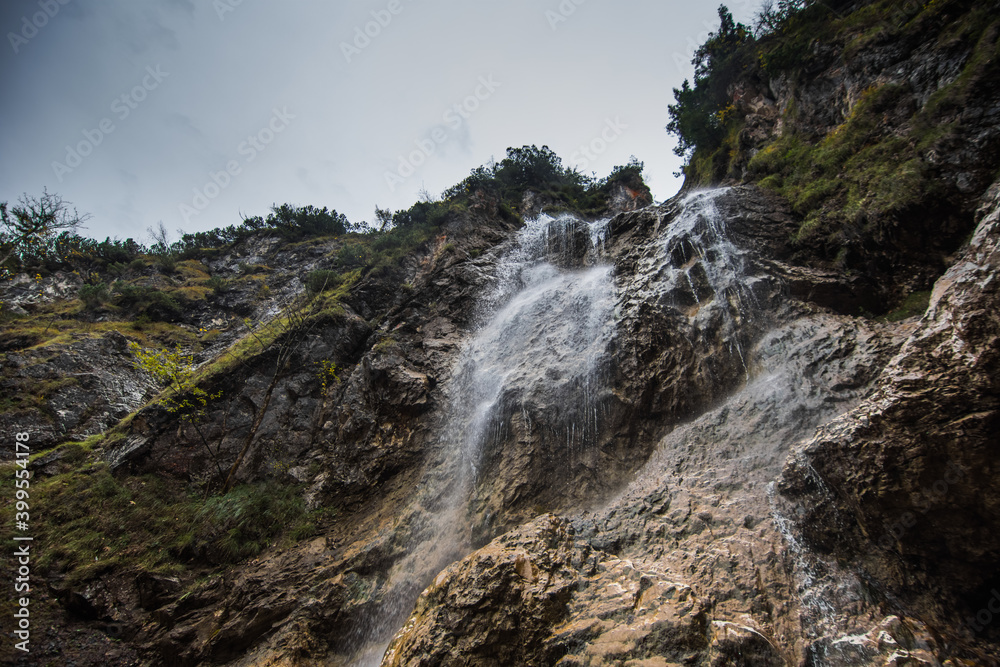 high little waterfall and steep rocks with green plants high little waterfall and steep rocks with green plants