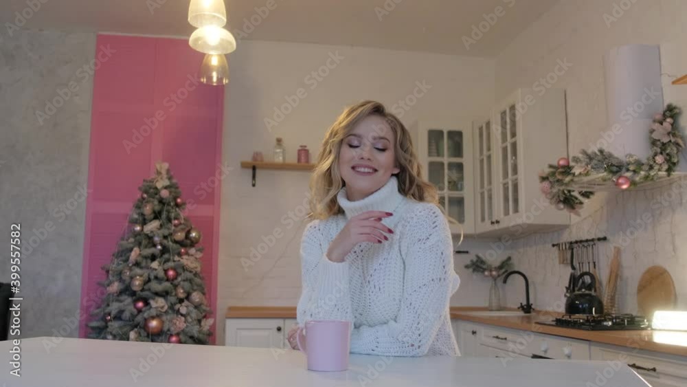 Cute blonde in a white sweater with a cup of coffee in the kitchen. Cute blonde in a white sweater with a cup of coffee in the kitchen.