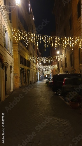 Cobblestone evening street illuminated with Christmas lights in Italy.