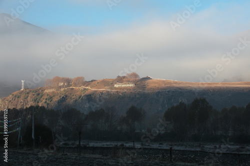 View of autumn scenery of Xinduqiao Town under sunrise and misty fog in Kangding County, Sichuan Province, China.  photo