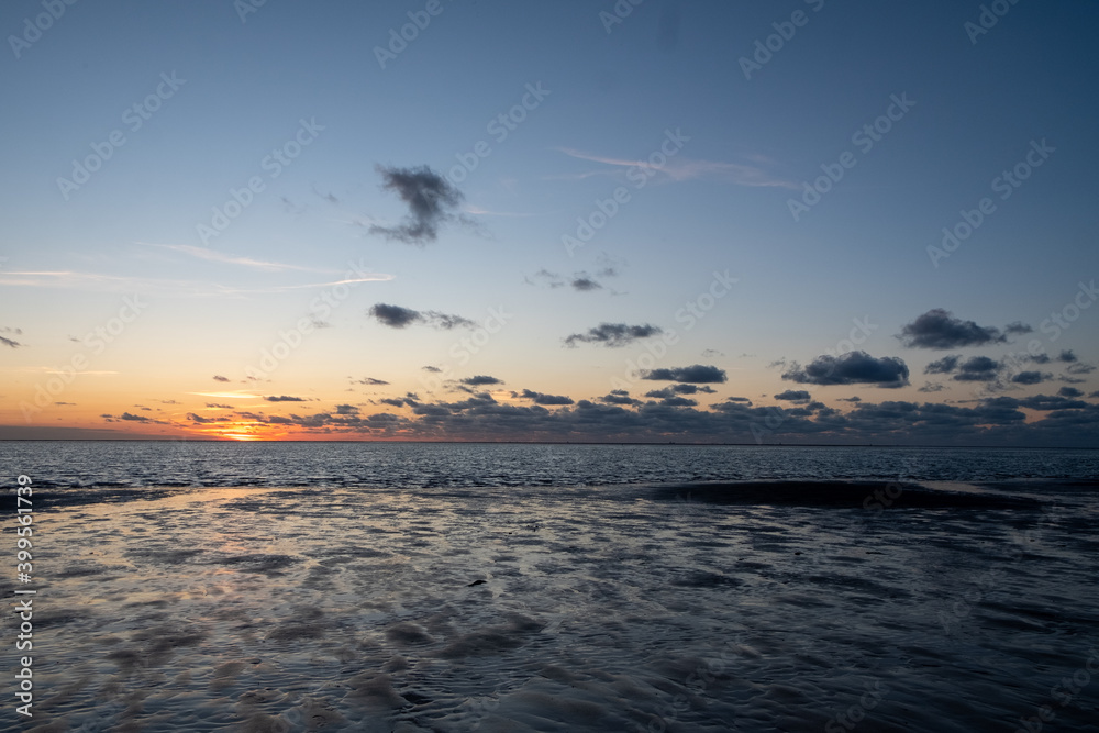 View of the setting sun shining on the Sea and reflected on the beach, clouds with sun-shining edges. Landscape. High quality photo showing concept of freedom and dreams View of the setting sun shining on the Sea and reflected on the beach, clouds with sun-shining edges. Landscape. High quality photo showing concept of freedom and dreams