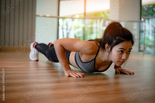 young Asian woman doing push ups in the gym