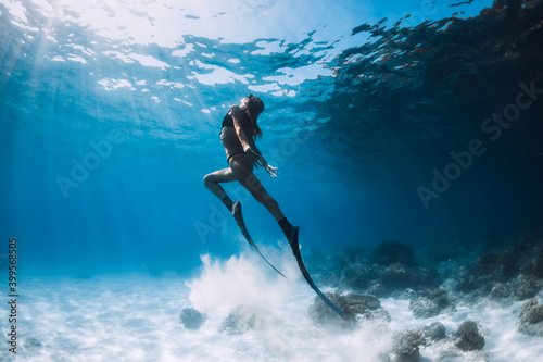 Woman freediver glides with sand over sandy bottom. Freediving underwater in Hawaii