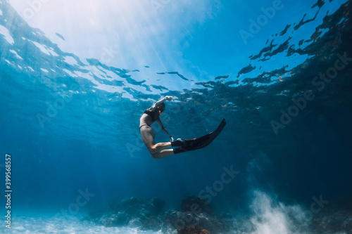 Woman freediver glides with sand over sandy bottom. Freediving underwater in Hawaii