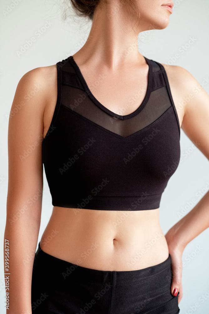 Woman sportswear. Clothing for branding. Active lifestyle. Fitness outfit. Female model with slim body posing in logo mockup black mesh crop top isolated on neutral background.