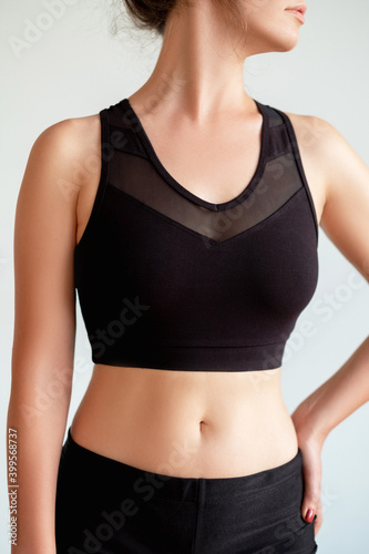 Woman sportswear. Clothing for branding. Active lifestyle. Fitness outfit. Female model with slim body posing in logo mockup black mesh crop top isolated on neutral background.