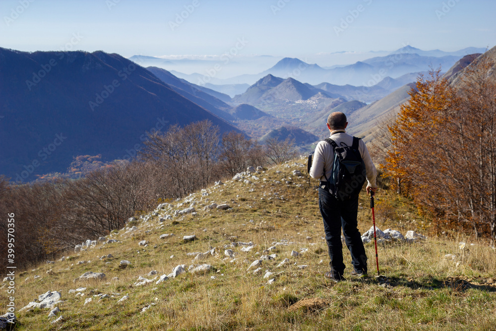 hiker on the top of a mountain in matese park and Letino in the background on Apennines in italy