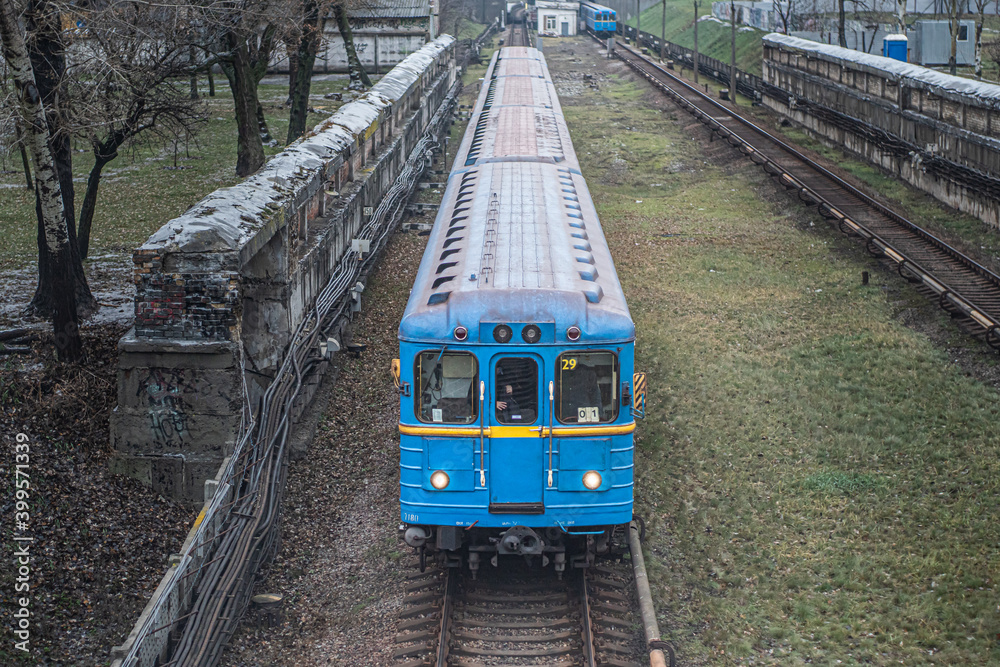 Naklejka premium Blue subway train Ezh runs along the railway in cloudy day. Yezh-3 train - Kyiv, Ukraine