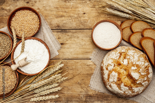 Fresh bread with wheat ears and a bowls of flour and grain