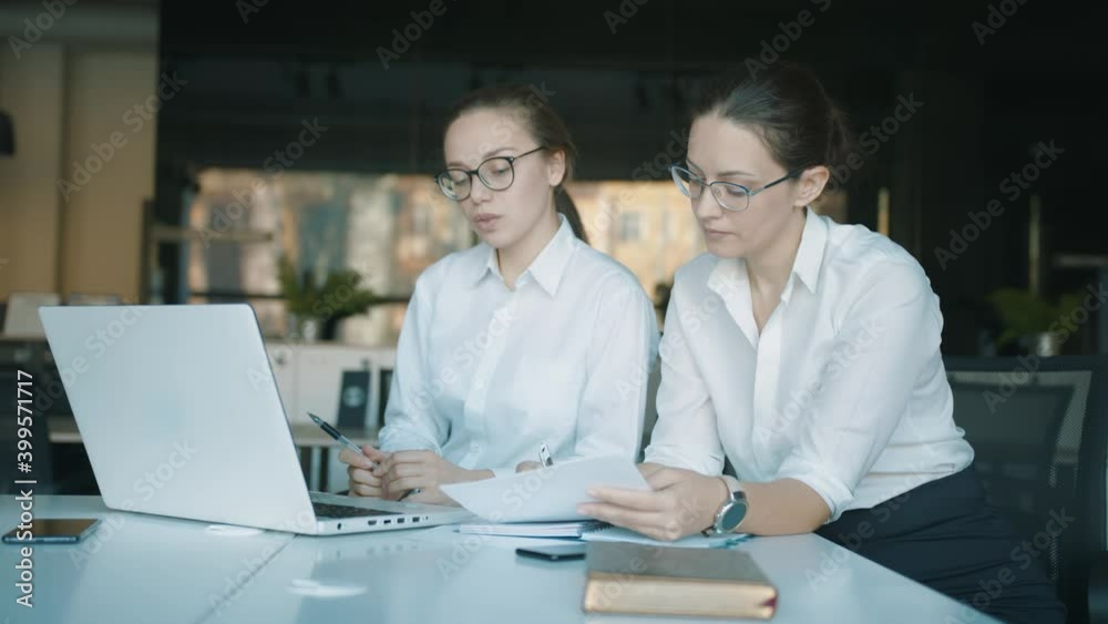 Online videoconference in modern office. Online discussion staff on laptop. Two young business women online meeting or presentation Online videoconference in modern office. Online discussion staff on laptop. Two young business women online meeting or presentation