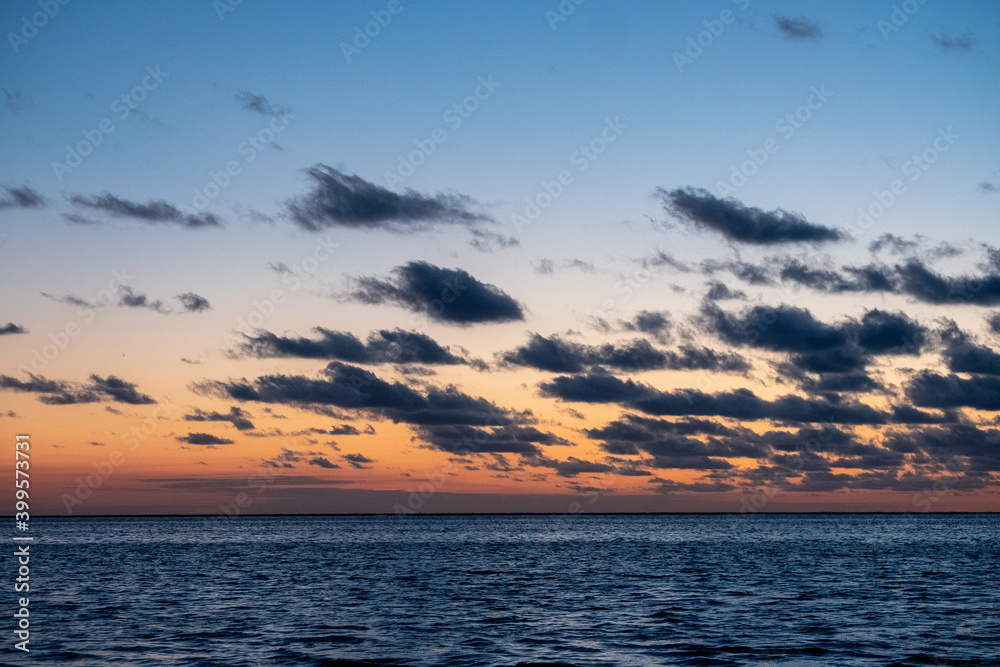 Obraz premium View of the setting sun shining on the Sea and reflected on the beach, clouds with sun-shining edges. Landscape. High quality photo showing concept of freedom and dreams