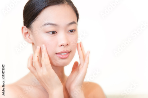 美容フェイシャルイメージ 両手にひらで頬を包む若く美しいアジア女性