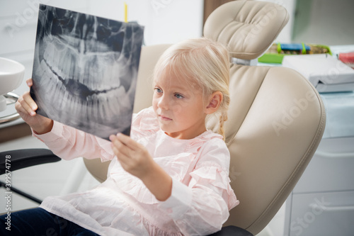A dentist shows a little girl an x-ray of real teeth.