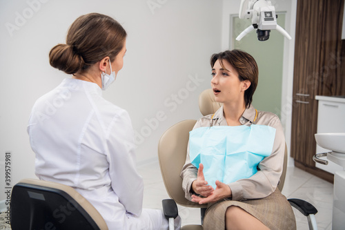 A young female dentist consulting her patient in the clinic.