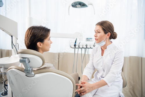 A young female dentist consulting her patient in the clinic.