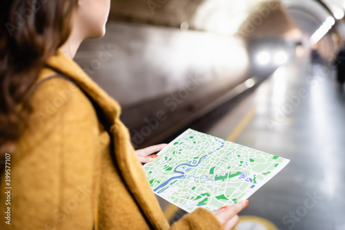 cropped view of woman holding city map on underground platform, blurred foreground