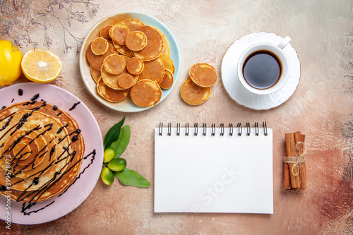 Overhead view of simple and decorated classic pancakes with fruits and notebook on colourful table photo