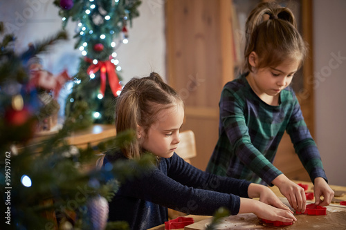 two cute sisters make and decorate Christmas gingerbread cookies