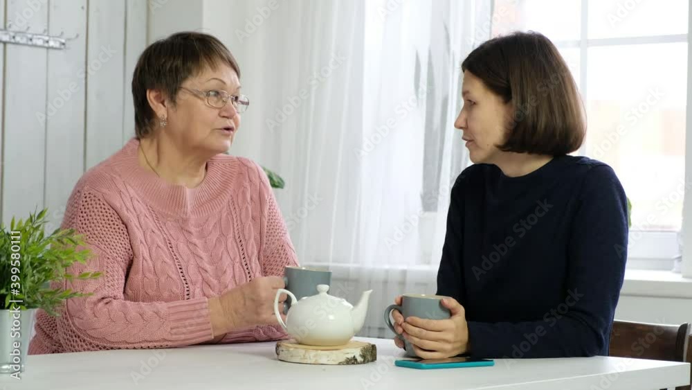 Adult woman talking with her senior mother in the kitchen, communication between generations Adult woman talking with her senior mother in the kitchen, communication between generations