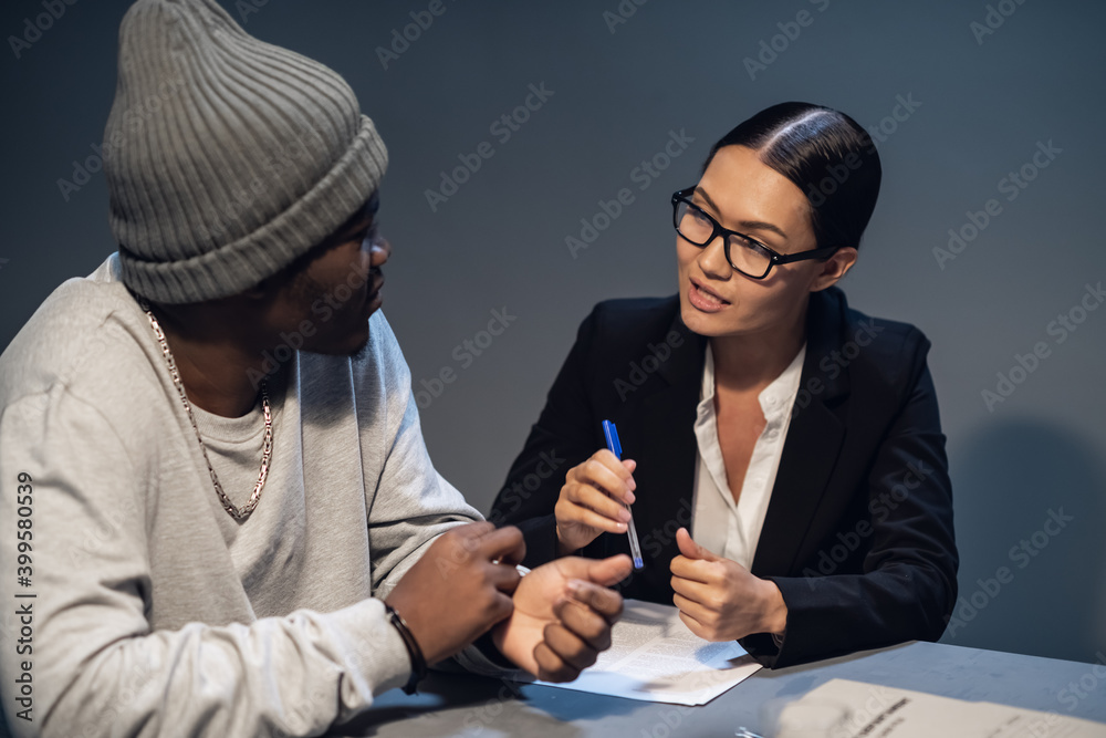 A pretty lawyer girl is having a conversation with a drug dealer client at the police station. - obrazy, fototapety, plakaty 