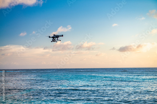 Modern drone overflying the ocean at sunset